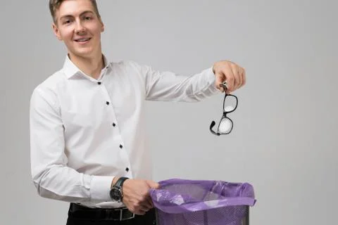 Young man throws glasses in trash isolated on white background Fotos Stock