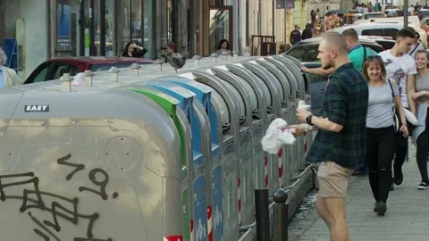 Young man throws plastic bags, garbage into a trash can containers with garbage. Stock Footage 132252947