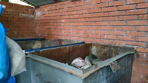 Young man throws white and blue garbage bags into dumpster Video stock 201635965