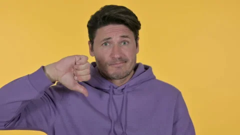 Young Man with Thumbs Down, Yellow Background Stock Footage 141681011