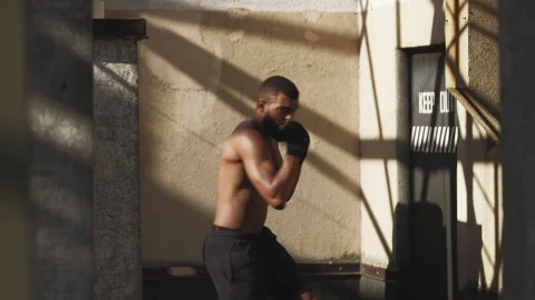 Young man with toned body practicing punches while shadow boxing on a rooftop Vídeos de archivo 331073203