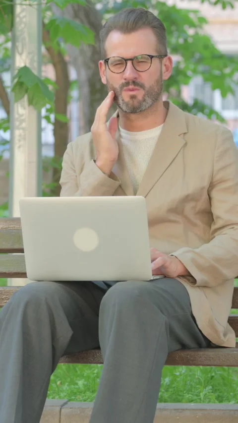 Young Man with Toothache Using Laptop while Sitting Outdoor, Vertical Video Video stock 319019744