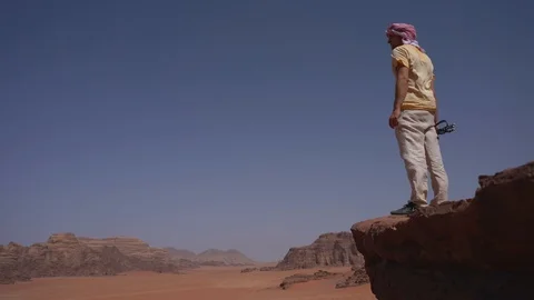Young man is to the top of cliff. Wadi Rum Stock Footage 126242811