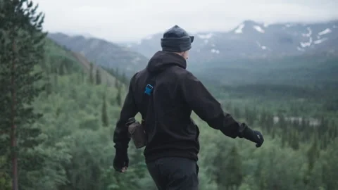 Young man on a top of mountain and uplifts his hands as a sign of victory Stock Footage 123350252