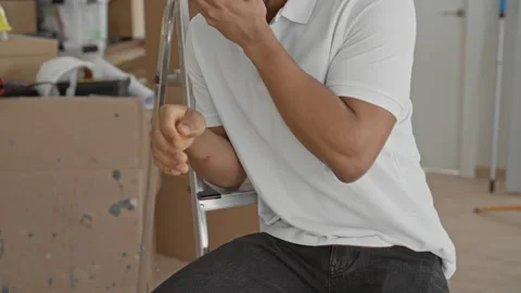 Young man touching face with hand and gripping ladder beside stacked moving.. Stock Footage 337438802