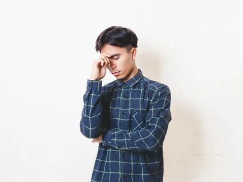 A young man touching his forehead with a worried expression, showing a stre.. Stock Photos