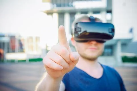 Young man touching space in front of him in virtual reality glasses headset s Stock Photos