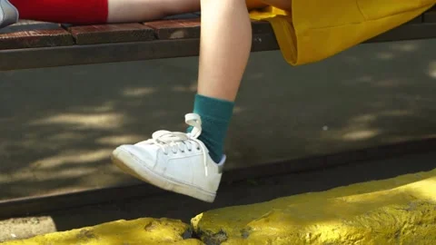 Young man tourist in different socks sits on bench and shakes his leg Stock Footage 225540821