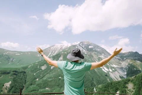Young man tourist raising his hands in the air and looking at the mountains Stock Photos