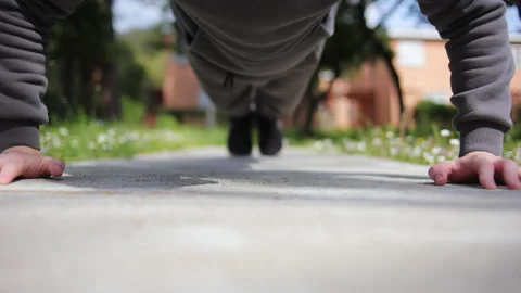 A young man in a tracksuit does push-ups in front of the camera with headphones Stock Footage 303541301
