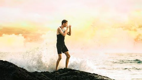 Young man training against the backdrop of the ocean Stock Photos