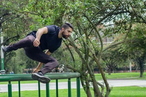 Young man training and doing parkour in a city park Stock Photos