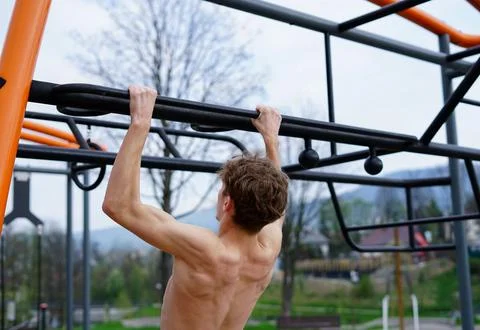 Young Man Training Outdoors with Pull-Ups on Fitness Bar Stock Photos