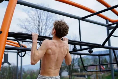 Young Man Training Outdoors with Pull-Ups on Fitness Bar Stock Photos