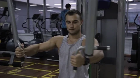 Young man is training in Pec Deck machine in gym indoors. Видео 85131062