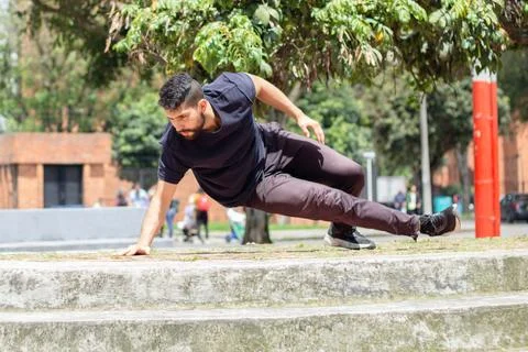 Young man training push ups on a chair in an outdoor park in the city Stock Photos