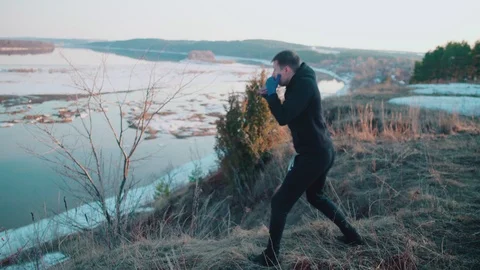 A young man trains on the edge of a cliff above the spring river with pieces of  库存影片 106510056