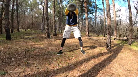 A young man trains with a kettlebell in the forest. Swing the kettlebell. Stock Footage 151164521