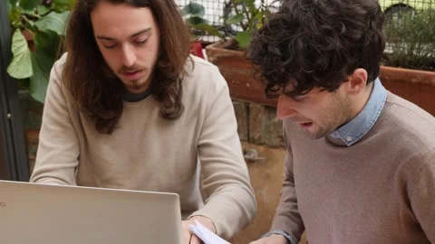 Young man transcribes to the pc the thesis that his friend dictates to him Stock Footage 240392413