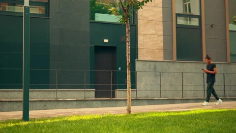 Young man in trendy clothes walking in city using smartphone Stock Footage 138794932