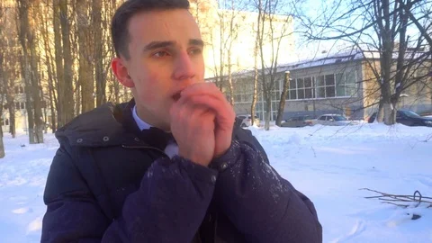 A young man tries to keep warm in winter, standing in the snow Stock Footage 85072333