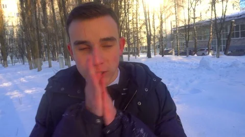 A young man tries to keep warm in winter, standing in the snow Stock Footage 85073068