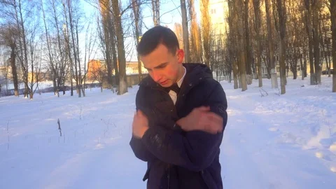 A young man tries to keep warm in winter, standing in the snow Video stock 85073321