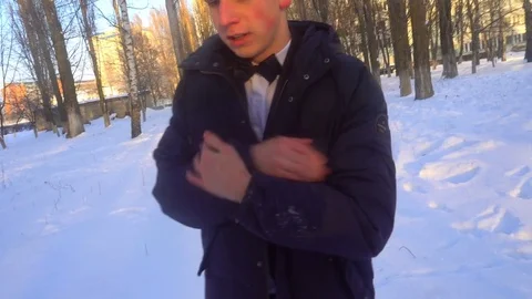 A young man tries to keep warm in winter, standing in the snow Video stock 85073515