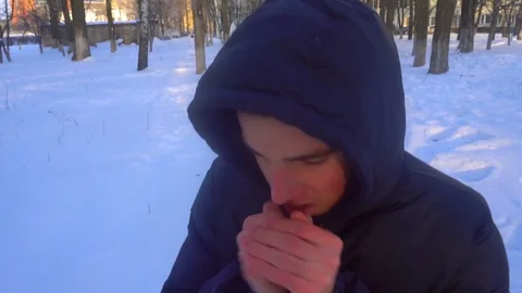 A young man tries to keep warm in winter, standing in the snow Stock Footage 85074095