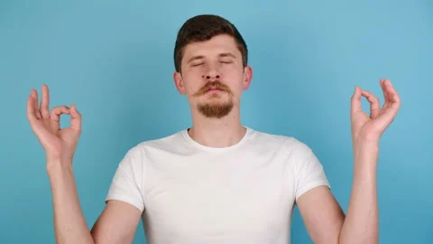 Young man tries to relax, meditates indoor, keeps hands in zen gesture Stock Footage 139340902
