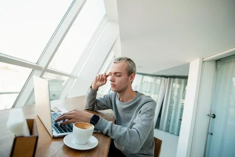 Young man tries to solve problem. Concentrated male programmer sits in front of Stock Photos