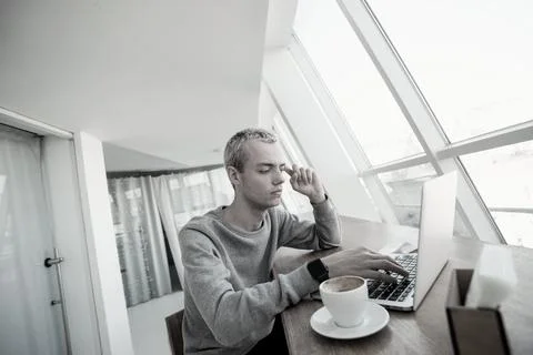 Young man tries to solve problem. Concentrated male programmer sits in front of Stock Photos