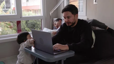 A young man tries to work while his two sons get in his way Stock Footage 245424467
