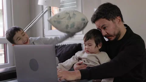 A young man tries to work while his two sons get in his way Stock Footage 245799680