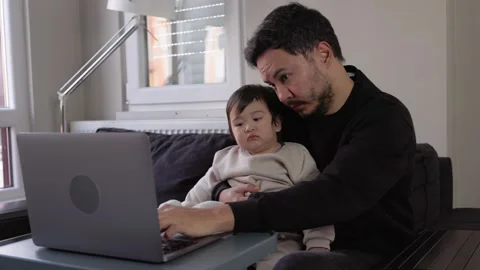 A young man tries to work while his two sons get in his way Stock Footage 245799725