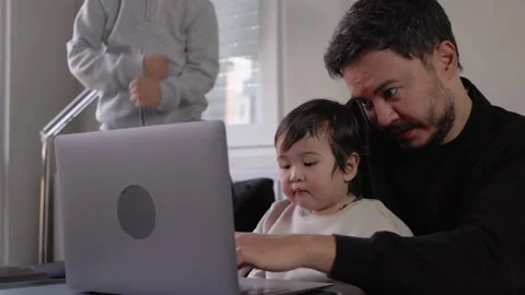 A young man tries to work while his two sons get in his way Stock Footage 245799982