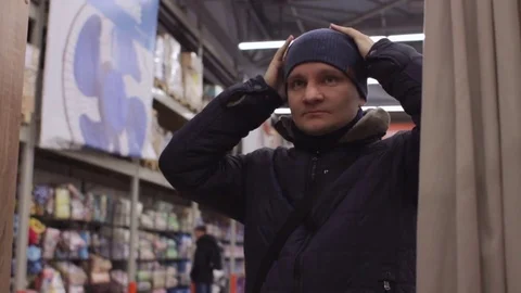 Young man trying caps and looking at mirror in the shop Stock Footage 74434023
