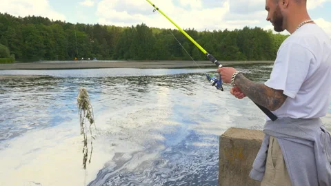 Young man trying to catch fish and catching weeds Stock Footage 93053970