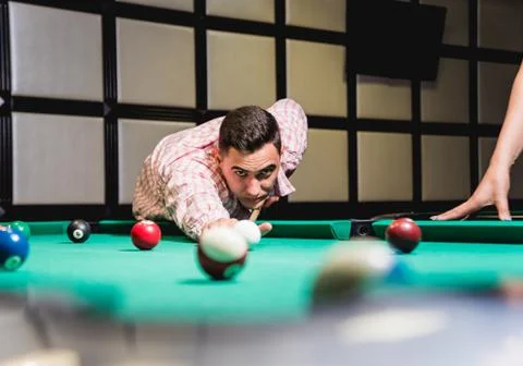 Young man trying to hit the ball in billiard. Stock Illustration