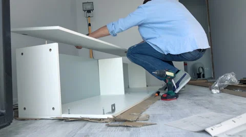 Young man trying to match pieces of furniture on floor at home Stock Footage 63074316