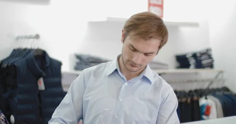 A young man trying on a red sweater Stock Footage 86080141