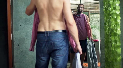 Young man trying shirts in front of the mirror in bathroom Video stock 55371877