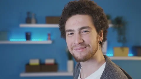 Young man turning towards camera smiling while standing sideways. Video stock 233029009