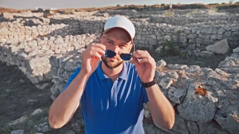Young man turns to the camera, takes off his sunglasses and smiles Stock Footage 195525267