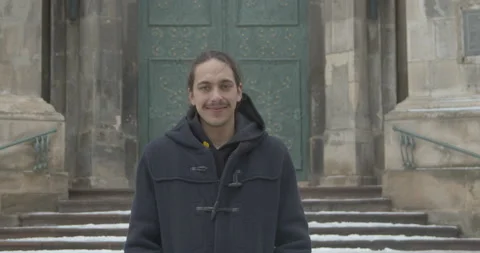 Young man turns head looking in camera smiling in city Stock Footage 170480449