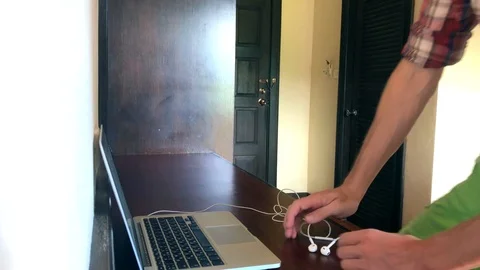 A young man turns on music and starts working at a laptop table Stock Footage 108810341