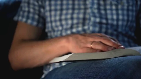 A young man turns a page of a thick book while reading. Self-education. Stock Footage 105799920