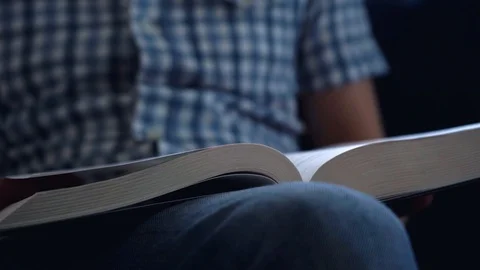 A young man turns a page of a thick book while reading. Self-education Stock Footage 105799941