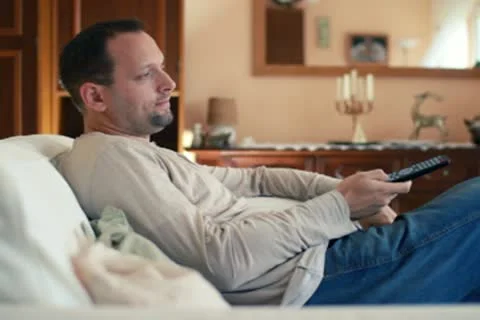 Young man with tv remote watching tv on sofa NTSC Stock Footage 10592891