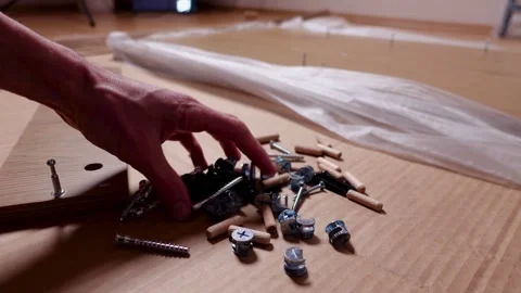 A young man twists a screw with a screwdriver into a board. Furniture assembly Stock Footage 240953798